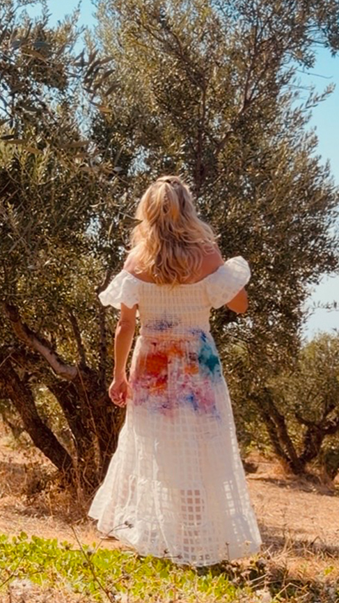 Patricia walking through olive grove in her painted white dress